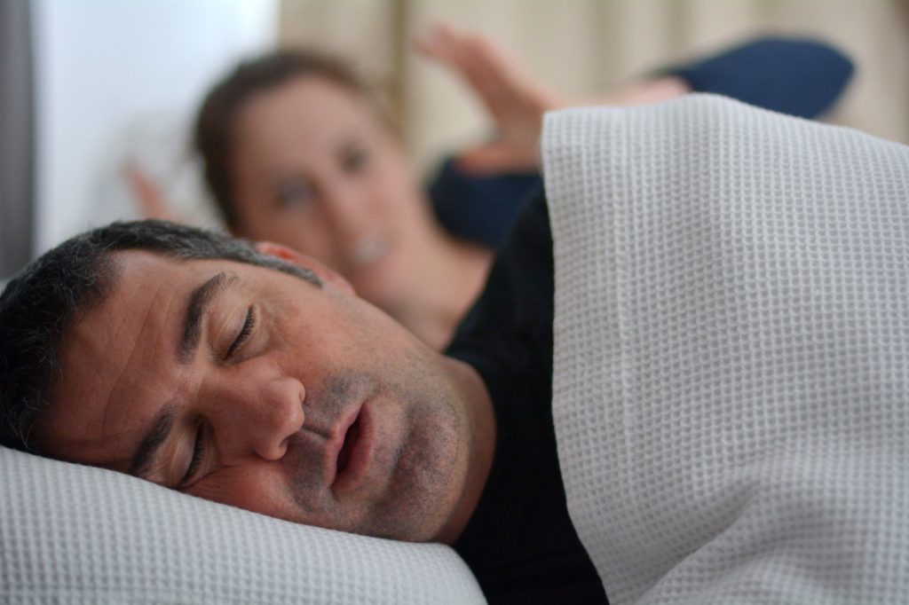 Couple in bed wife is upset because husband is snoring 