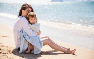 Single mom sitting on beach with daughter thinking about the right policy