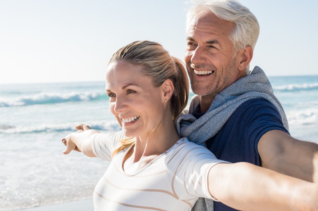 Man and Women on Beach thinking about retirement and their whole life policy